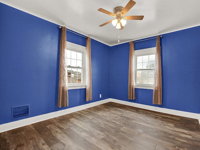 spare room with wood finished floors, baseboards, a ceiling fan, and visible vents