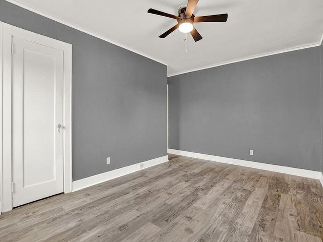 empty room with ornamental molding, ceiling fan, wood finished floors, and baseboards