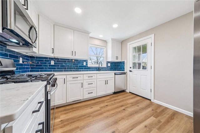 226 Old Leechburg Rd, Plum Boro, PA 15239 - kitchen with light wood-style flooring, tasteful backsplash, white cabinetry, appliances with stainless steel finishes, and baseboards