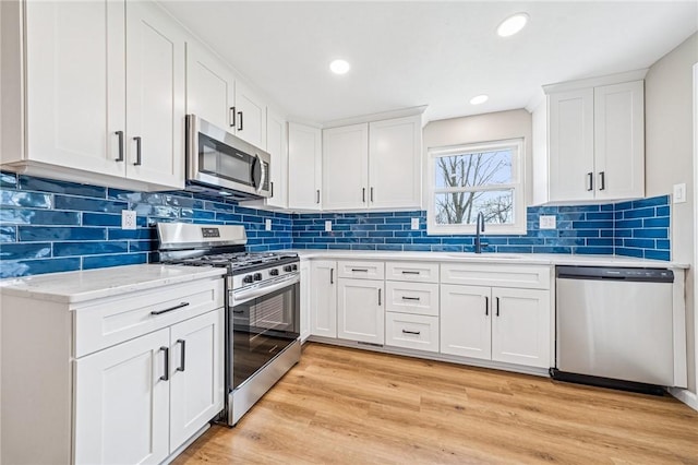 226 Old Leechburg Rd, Plum Boro, PA 15239 - kitchen featuring light wood-style floors, white cabinetry, appliances with stainless steel finishes, a sink, and decorative backsplash