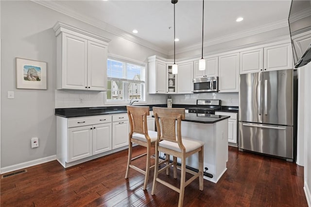 kitchen with appliances with stainless steel finishes, dark countertops, white cabinetry, and visible vents