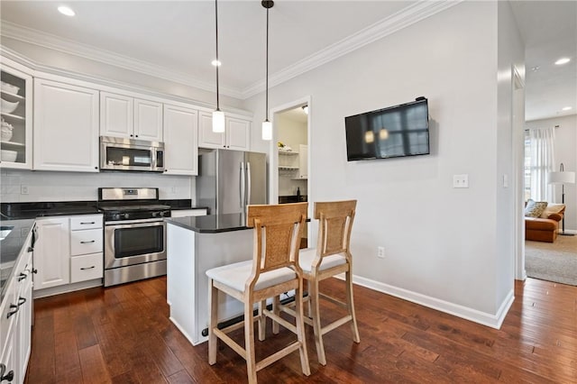 kitchen featuring tasteful backsplash, appliances with stainless steel finishes, a breakfast bar area, and dark wood-style floors