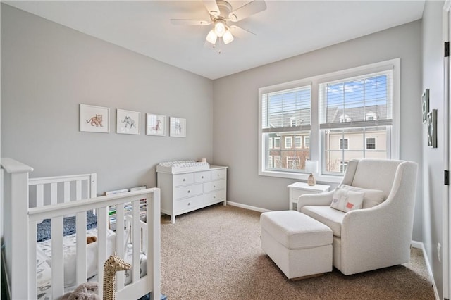 bedroom with carpet floors, ceiling fan, baseboards, and a nursery area