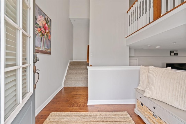 entryway featuring baseboards, wood finished floors, and stairs