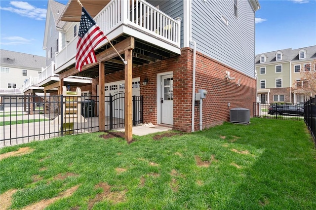 view of side of home with central AC, a yard, fence, brick siding, and a garage