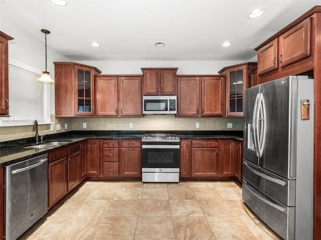 kitchen with tasteful backsplash, glass insert cabinets, appliances with stainless steel finishes, a sink, and hanging light fixtures