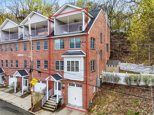 multi unit property with ceiling fan, brick siding, fence, a balcony, and an attached garage
