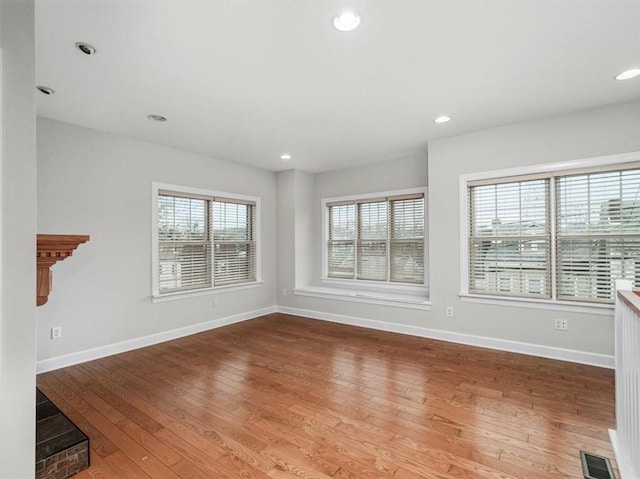 unfurnished living room featuring visible vents, baseboards, recessed lighting, and wood-type flooring