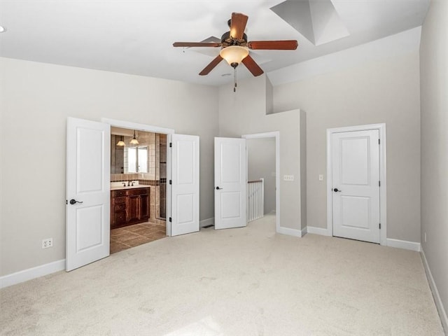 unfurnished bedroom featuring ensuite bathroom, a ceiling fan, light carpet, lofted ceiling, and baseboards