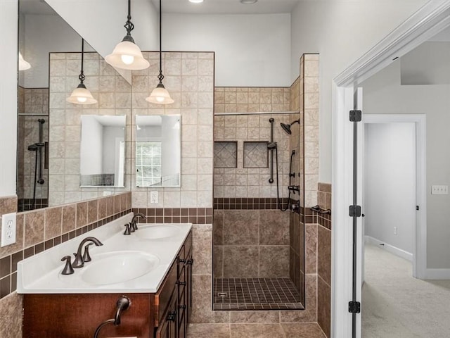 full bath with tiled shower, double vanity, and a sink