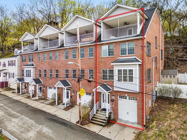 multi unit property with a balcony, a garage, concrete driveway, and brick siding