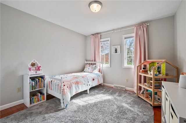 bedroom with visible vents, baseboards, and wood finished floors