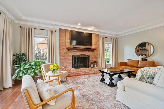 living area with hardwood / wood-style floors, a healthy amount of sunlight, a fireplace, and ornamental molding