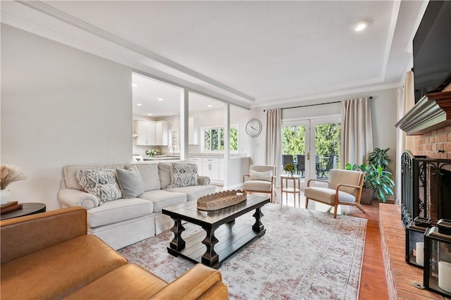 living room with ornamental molding, recessed lighting, a fireplace, french doors, and light wood finished floors