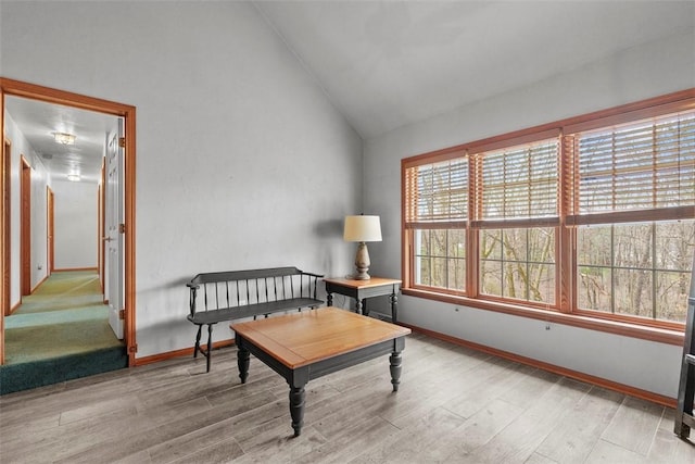sitting room with light wood finished floors, baseboards, and vaulted ceiling