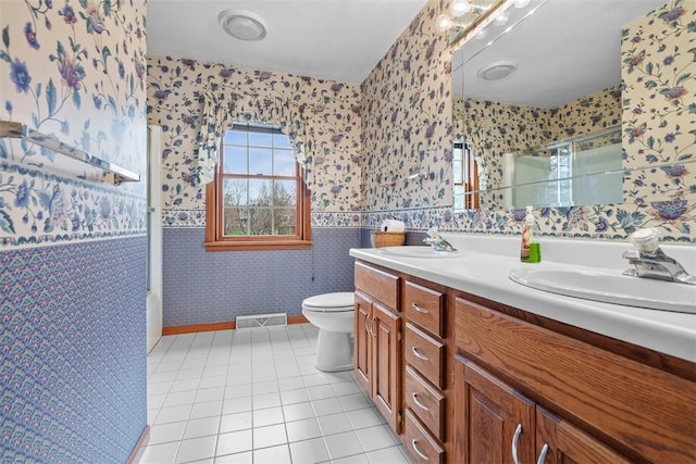 bathroom with wallpapered walls, a stall shower, tile patterned floors, visible vents, and a sink