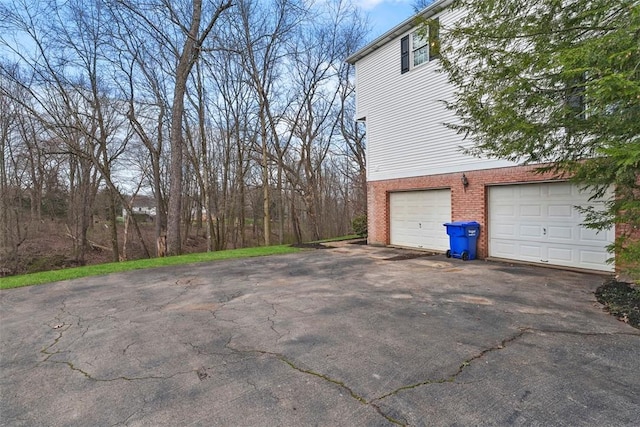 exterior space with a garage, brick siding, and driveway