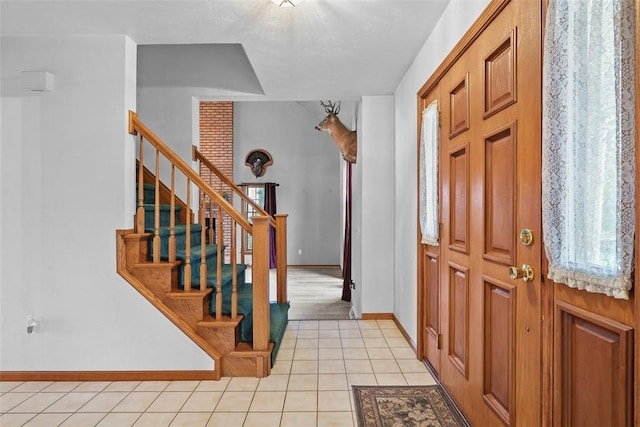 foyer entrance featuring light tile patterned floors, baseboards, and stairway