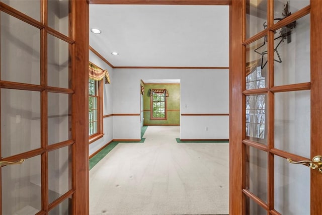 hallway with crown molding, french doors, baseboards, and carpet floors