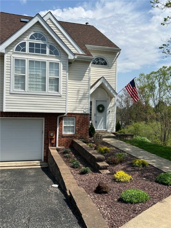 view of front of property with brick siding, a garage, driveway, and a shingled roof