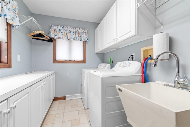 laundry area featuring cabinet space, baseboards, washing machine and dryer, and a sink