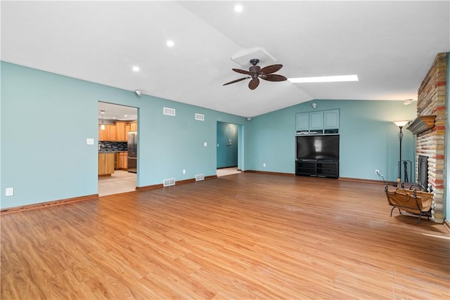 unfurnished living room featuring a ceiling fan, a fireplace, vaulted ceiling, baseboards, and light wood finished floors