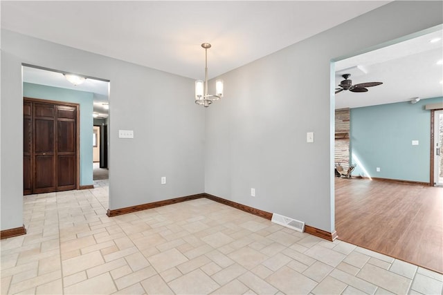 empty room featuring baseboards, visible vents, and ceiling fan with notable chandelier