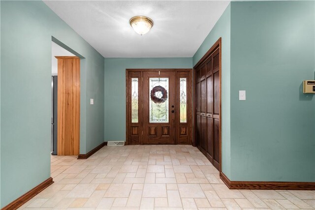 foyer entrance featuring baseboards and visible vents