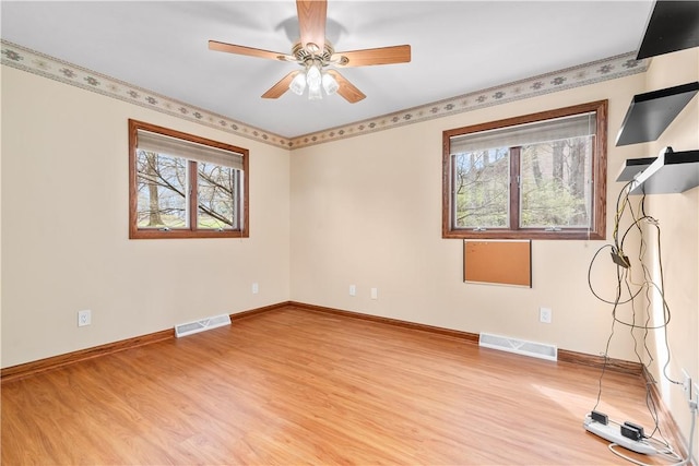 empty room with visible vents, light wood finished floors, and a wealth of natural light