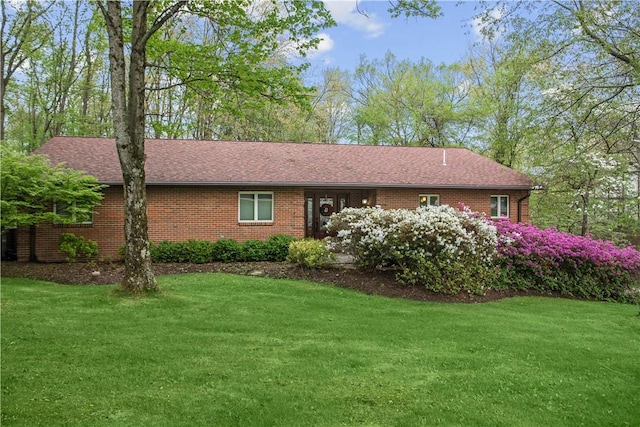 view of front of house featuring brick siding, roof with shingles, and a front yard