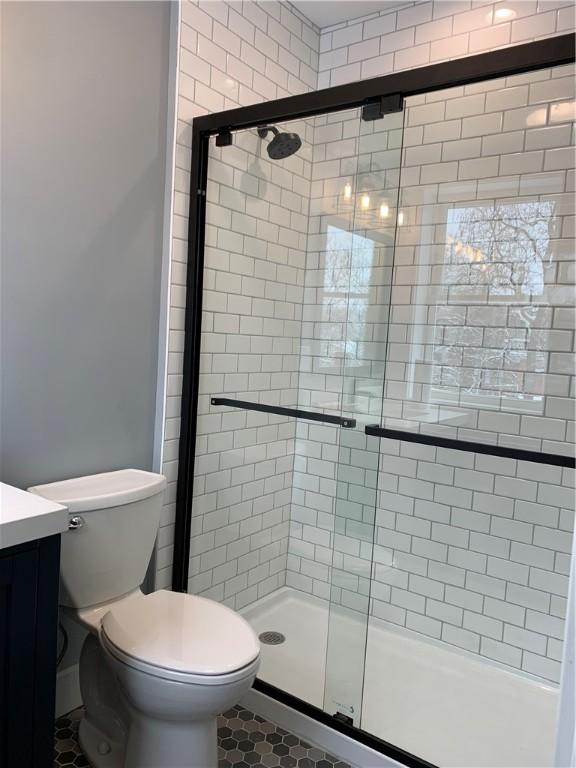 full bathroom with toilet, a shower stall, and tile patterned flooring
