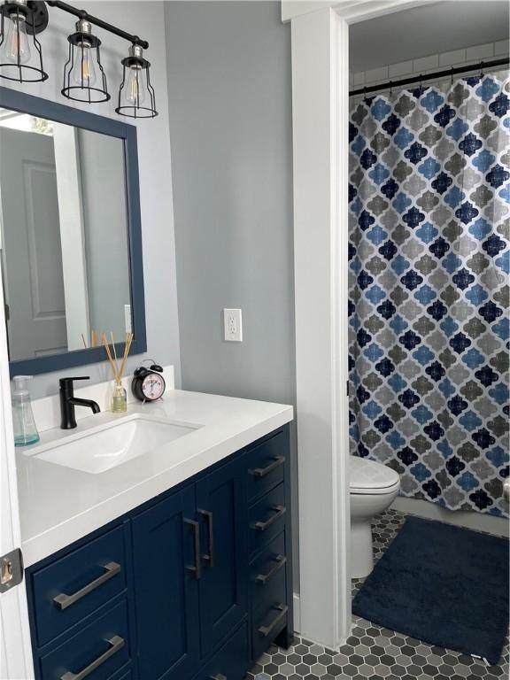 bathroom featuring tile patterned flooring, toilet, curtained shower, and vanity