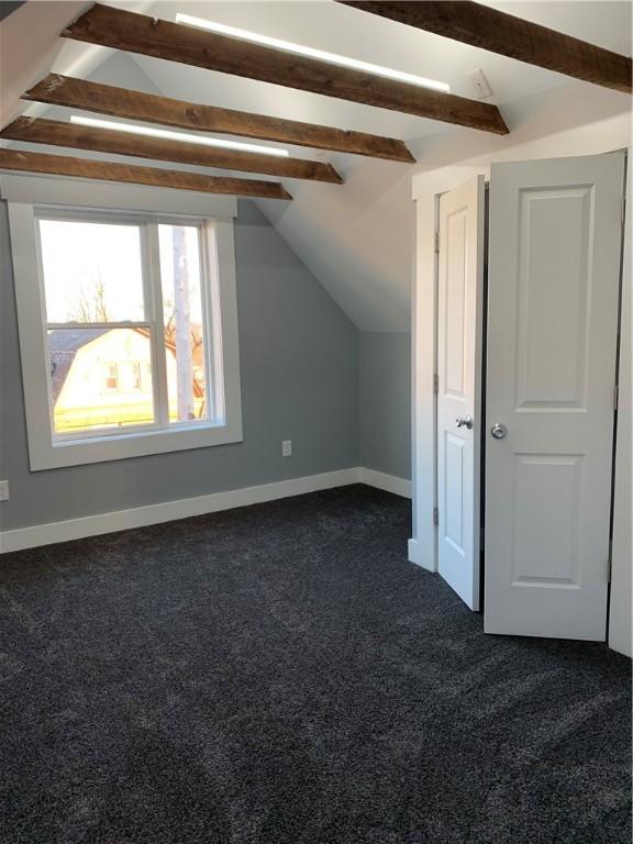 additional living space featuring vaulted ceiling with beams, baseboards, and dark carpet