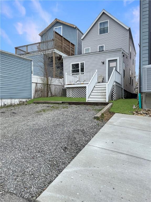 rear view of property with a deck, central air condition unit, and fence