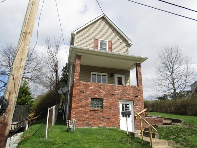 view of front of home with brick siding, a front lawn, and fence