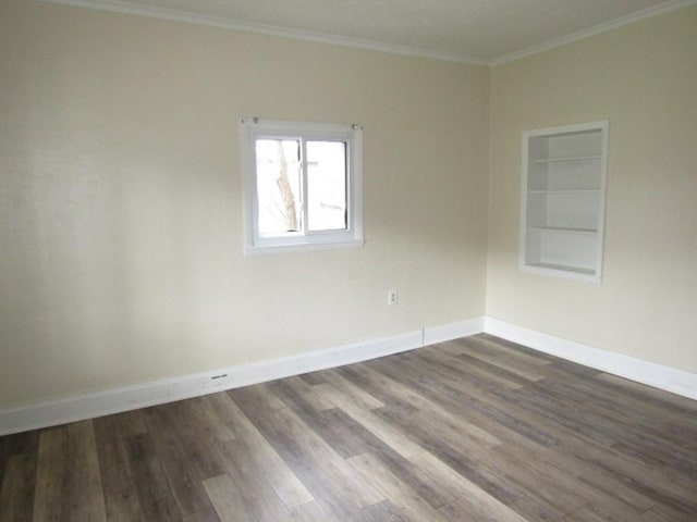 empty room with crown molding, dark wood-style flooring, baseboards, and built in shelves