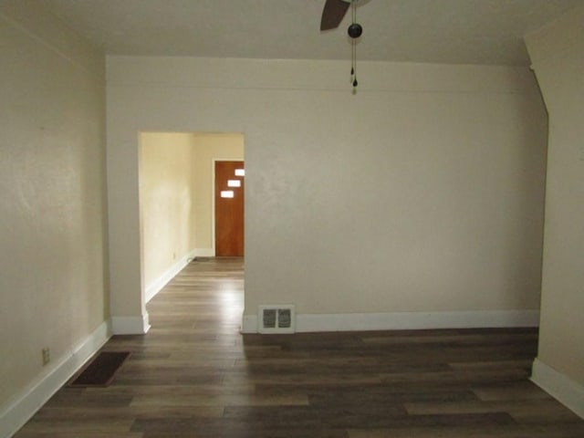 spare room with dark wood-style flooring, visible vents, baseboards, and a ceiling fan