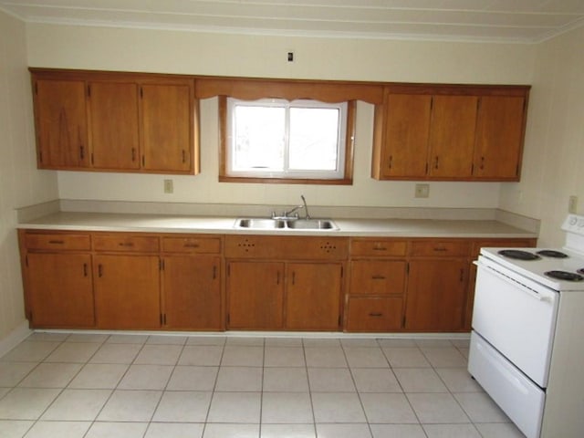 kitchen with brown cabinets, electric range, light countertops, and a sink