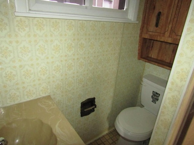 bathroom with toilet and wallpapered walls