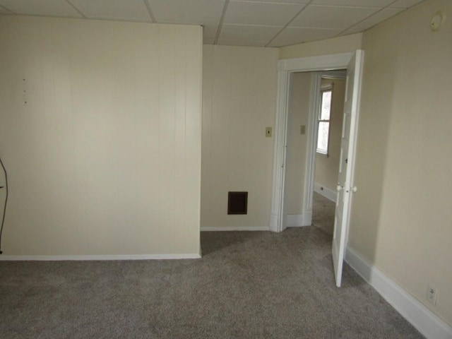 carpeted spare room with visible vents, a drop ceiling, and baseboards