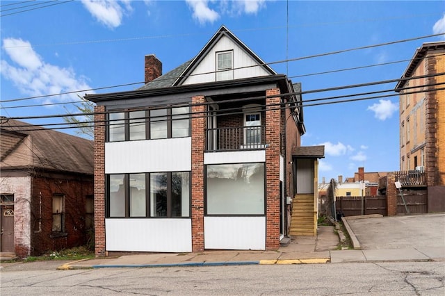 view of front of home featuring brick siding and a balcony