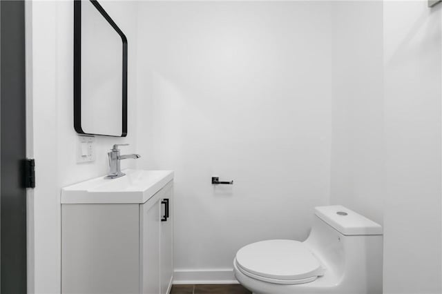 half bath featuring toilet, vanity, and baseboards