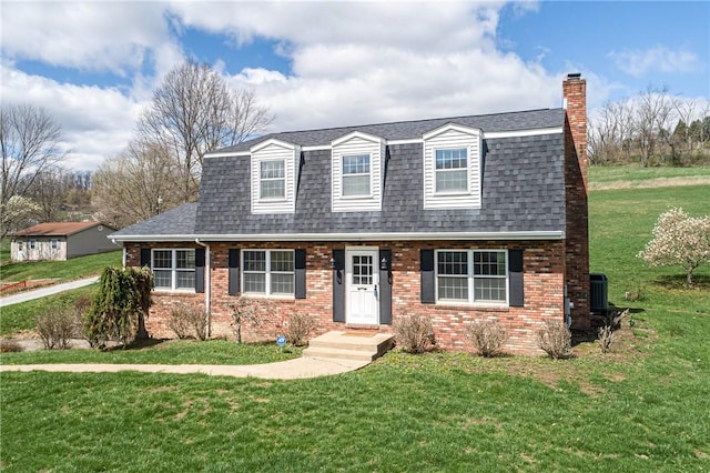 colonial inspired home featuring a front yard, brick siding, a chimney, and a shingled roof