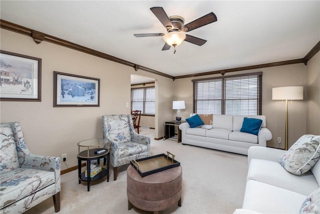 living area with light carpet, baseboards, crown molding, and ceiling fan