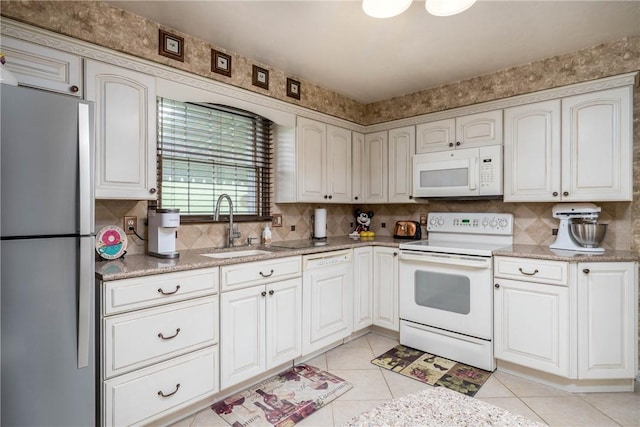 kitchen with white appliances, a sink, light tile patterned floors, and decorative backsplash