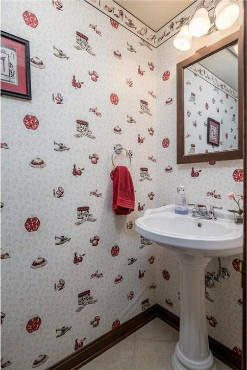 bathroom with wallpapered walls, baseboards, and tile patterned flooring