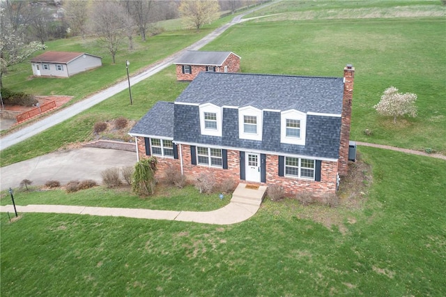 view of front facade featuring brick siding, a shingled roof, a gambrel roof, and a chimney