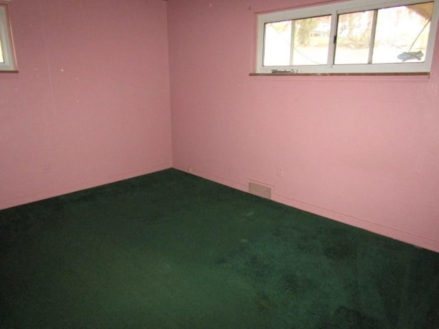 spare room with dark carpet, baseboards, and visible vents