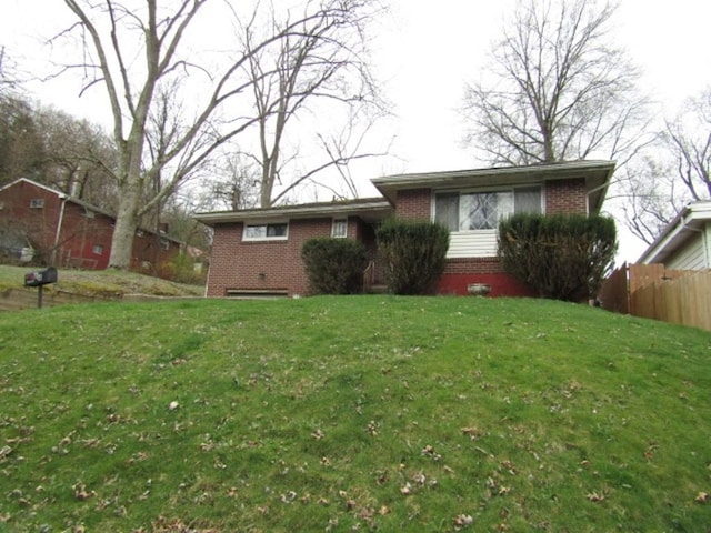 view of front of house with brick siding, a front yard, and fence