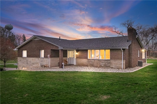 view of front facade featuring a shingled roof, stone siding, a chimney, brick siding, and a front lawn